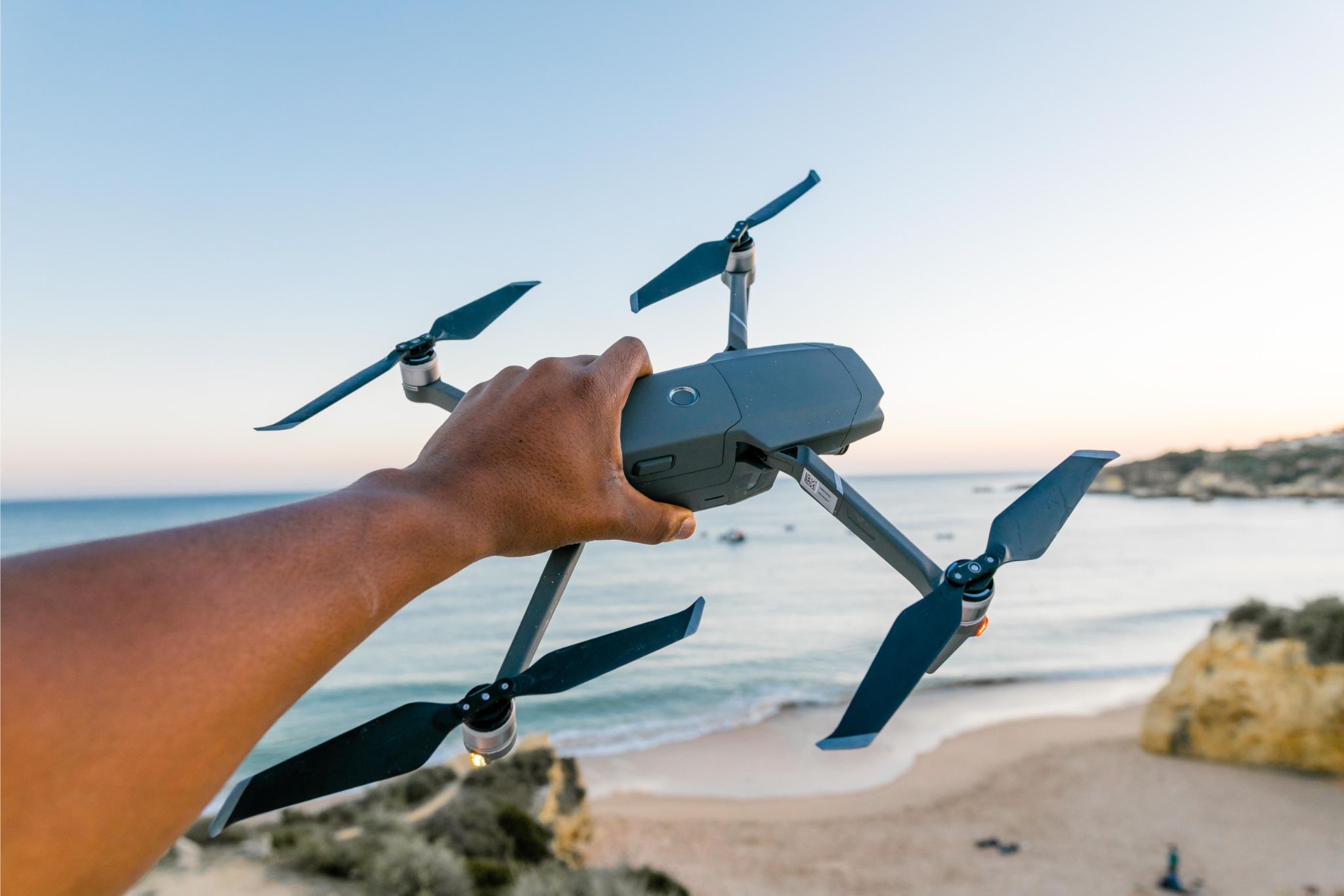Hand holding a quadcopter and beach on the background